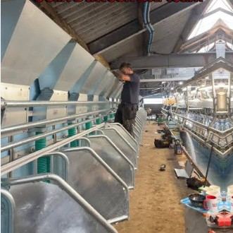 Engineer working overhead in a milking parlour
